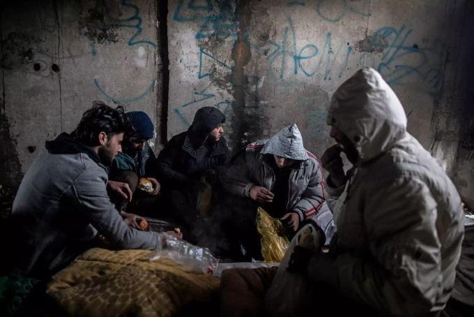Eine Gruppe syrischer Migranten frühstückt in einem verlassenen Gebäude, in dem sie Unterschlupf gesucht hatten. Die Flüchtlinge wollen über die EU-Grenze nach Kroatien gelangen. Migranten