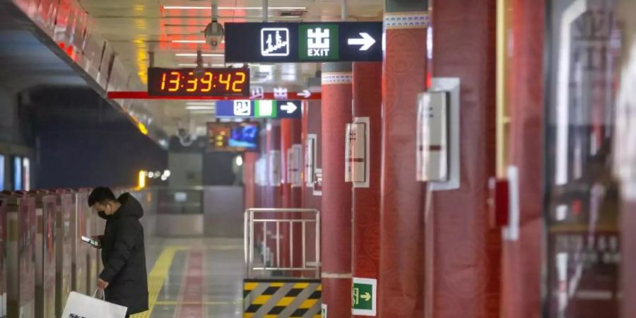Ein Mann mit Mundschutz wartet an einer fast leeren U-Bahn-Station: Die Furcht vor dem Coronavirus hat viele Menschen in der chinesischen Hauptstadt zu Hause gehalten. Foto: Mark Schiefelbein/AP/dpa