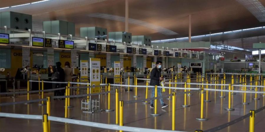 Ein Mann mit Mundschutzmaske im leeren Terminal eines Flughafens. Foto: Emilio Morenatti/AP/dpa