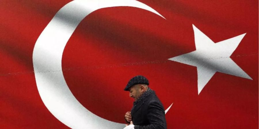 Ein Mann geht an einer türkischen Flagge vorbei. Foto: Ali Unal/AP