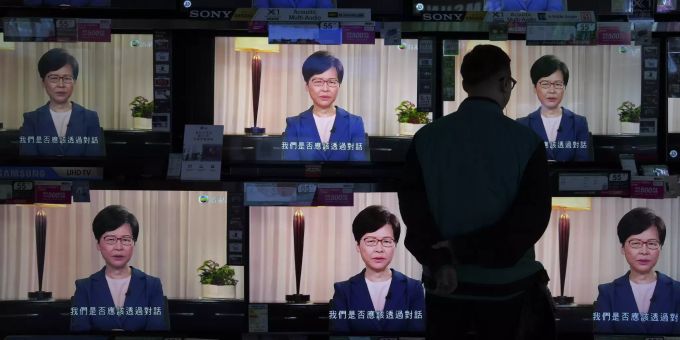 Hongkong-Chefin Carrie Lam spricht im Fernsehen. Ein Mann schaut auf diversen Fernsehern zu. APTOPIX Hong Kong Protests