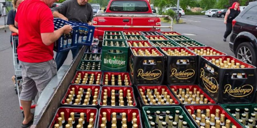 Eine Frau und zwei Männer laden Bierkästen in der Nähe eines örtlichen Supermarktes auf einen Anhänger. Das ganze Bier des Supermarktes wurde in einer Aktion von Bürgern und des IBZ (Internationalen Begegnungszentrum des Kloster Sankt Marienthal) aufgekauft. Foto: Daniel Schäfer