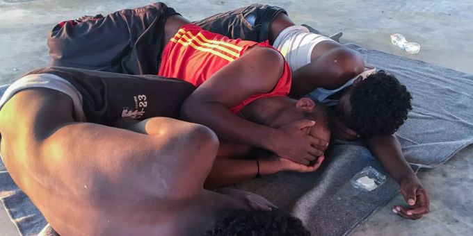 Gerettete Migranten ruhen sich an der Küste etwa 100 Kilometer östlich von Tripolis aus. Migranten in Libyen