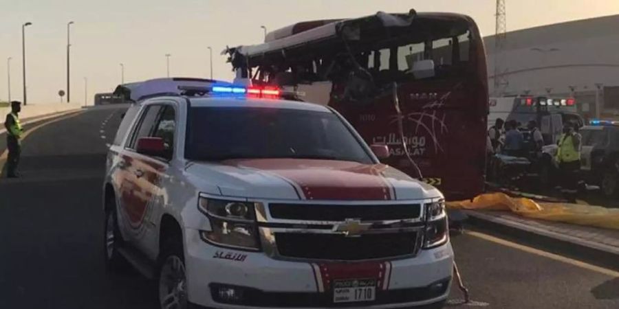 Ein Polizeiwagen steht an der Unfallstelle neben dem aufgerissenen Bus. Foto: Dubai Police HQ/AP