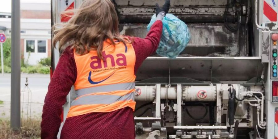 Eine junge Frau wirft bei einem Aktionstag vom Zweckverband Abfallwirtschaft Region Hannover aha einen Sack mit Altpapier in einen Müllwagen. Foto: Julian Stratenschulte/dpa