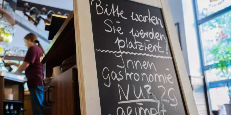 Eine Tafel mit der Aufschrift «Innengastronomie - Nur 2G - geimpft - genesen» steht in Schadt’s Brauerei Gasthaus. Foto: Julian Stratenschulte/dpa