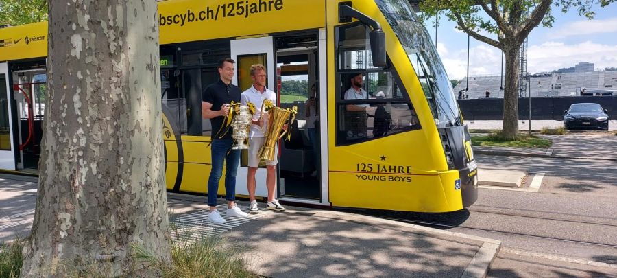 Sandro Lauper und Fabian Lustenberger posieren mit den Titeln der Saison 2022/23 vor dem «YB-Tram».