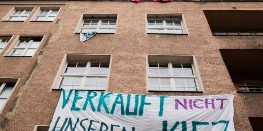 Ein Transparent gegen Investoren und Gentrifizierung hängt an der Fassade eines Hauses in Berlin-Neukölln. Foto: Christoph Soeder/dpa