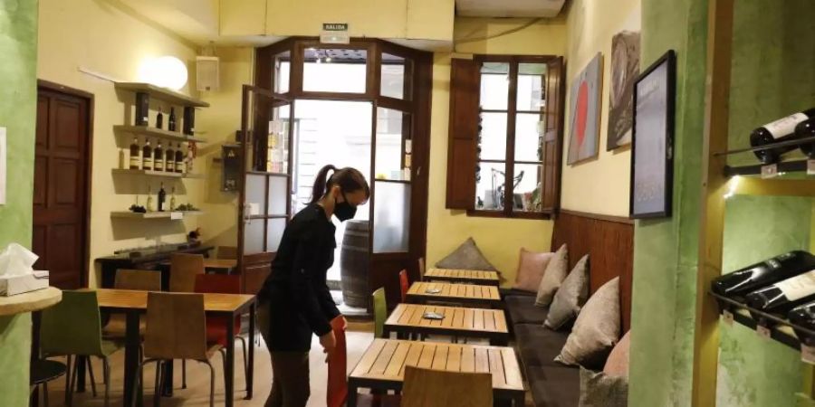 Eine Kellnerin mit Maske bereitet in Palma den Innenraum eines Restaurants für das Tagesgeschehen vor. Foto: Clara Margais/dpa