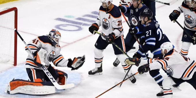 Der Torwart der Edmonton Oilers, Mike Smith (41), pariert einen Schuss der Winnipeg Jets, während die Spieler während des ersten Drittels eines NHL-Spiels gegen die Winnipeg Jets nach dem Abpraller suchen. Edmonton Oilers