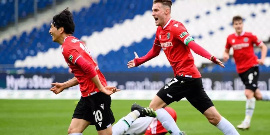 Genki Haraguchi (l) und Marvin Ducksch retteten Hannover 96 noch einen Punkt gegen den HSV. Foto: Swen Pförtner/dpa-POOL/dpa