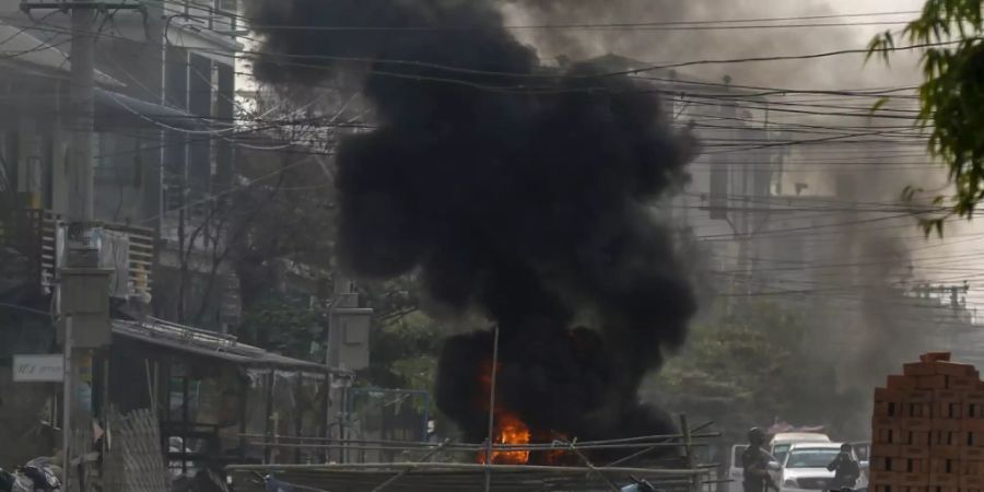 Bewaffnete Polizisten und Soldaten aus Myanmar erreichen eine Barrikade, die von Putschgegnern in Mandalay errichtet wurde. In vielen Städten gibt es weiterhin Proteste gegen die Militär-Junta im Land. Foto: Uncredited/AP/dpa