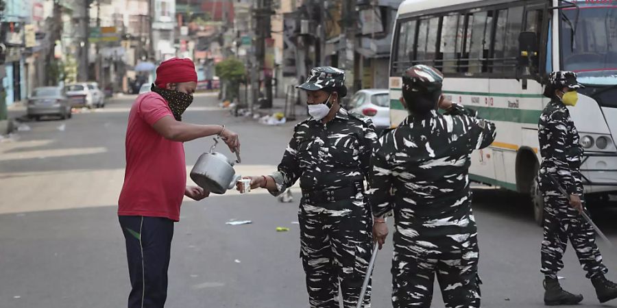 Ein Mann versorgt paramilitärisches Personal mit Trinkwasser. Indien hat zuletzt mehr als 343 000 Tagesneuinfektionen und 4000 Todesfälle in der gleichen Zeitperiode erfasst. Foto: Anupam Nath/AP/dpa