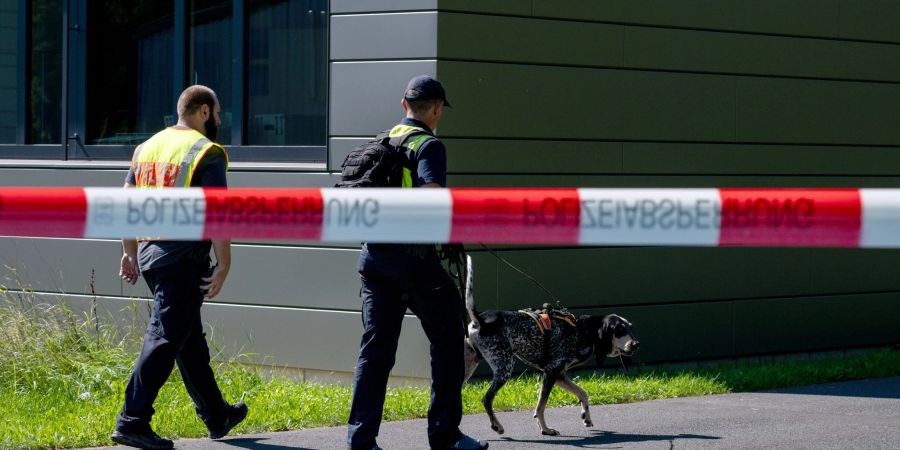 Polizeibeamte ermitteln mit einem Spürhund am Schulzentrum in Lohr am Main, wo der tote 14-Jährige gefunden wurde.