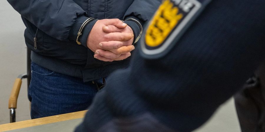 Der angeklagte 41-Jährige steht mit Handschellen im Landgericht. Er gab zu, im Frühjahr 2023 auf einem Schulhof seine siebenjährige Tochter ermordet zu haben.