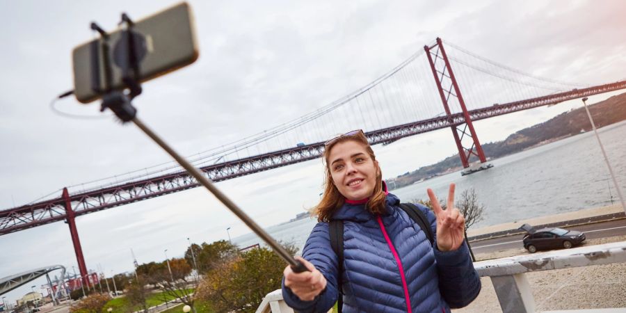 Frau macht Selfie mit Stick vor Golden Gate Bridge in der USA.