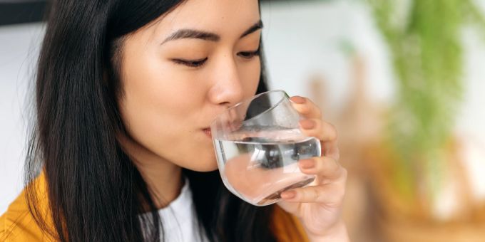 Ausreichend Flüssigkeit ist für das Gehirn essenziell. Frau trinkt ein Glas Wasser