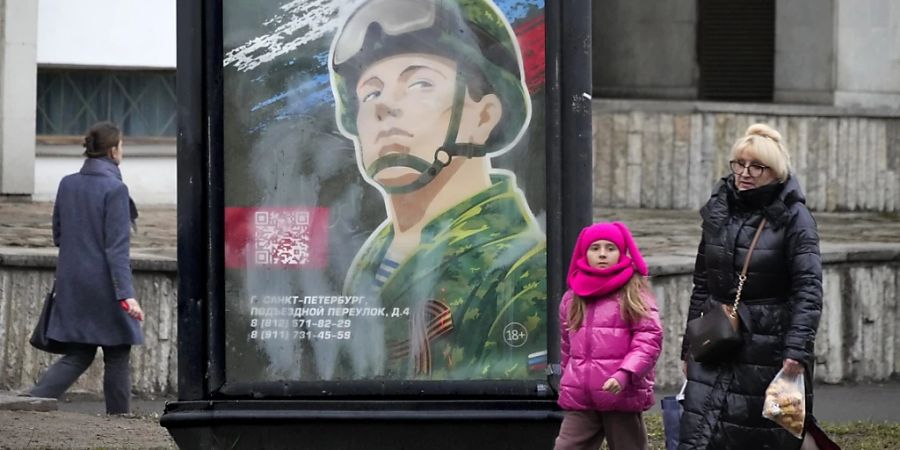 Menschen gehen im russischen St. Petersburg an einem Rekrutierungsplakat der Armee mit der Aufschrift «Militärdienst unter Vertrag in den Streitkräften» vorbei. Foto: Evgeniy Maloletka/AP/dpa