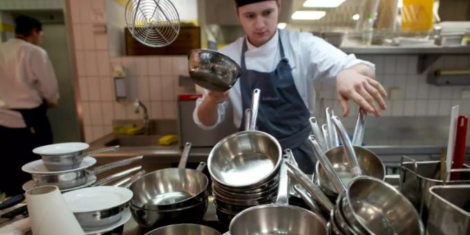 Ein Koch sortiert Töpfe in einem Berliner Restaurant Ein Koch sortiert Töpfe in einem Berliner Restaurant
