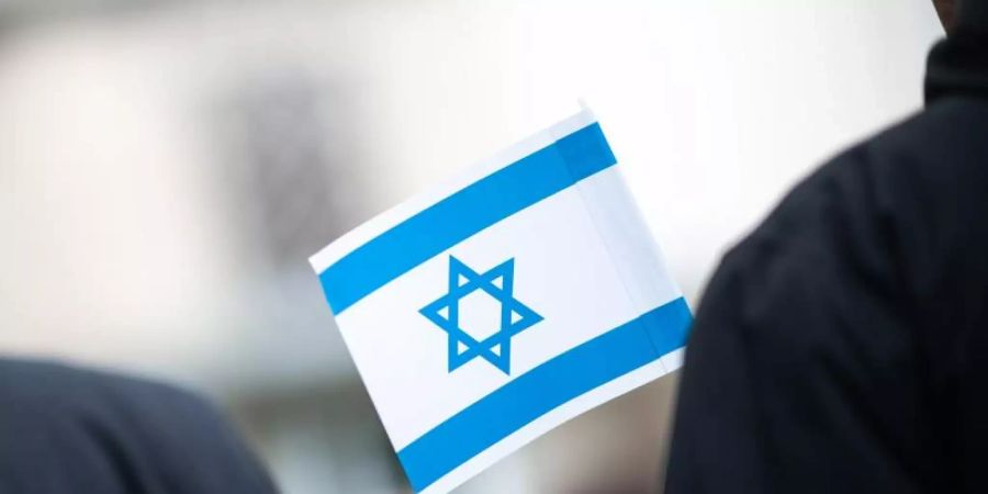 Bei einer Solidaritätskundgebung vor einer Synagoge hält ein Teilnehmer eine israelische Flagge in der Hand. Foto: Jonas Güttler/dpa