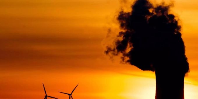 Zwei Windräder und ein Kohlekraftwerk im Licht der aufgehenden Sonne. (Symbolbild) Kohle Wind