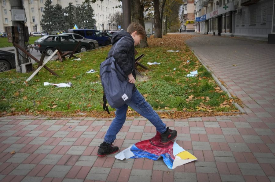 Ein Junge trampelt in Cherson auf einer russischen Fahne herum.