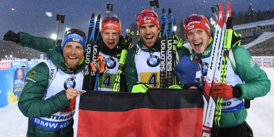 Erik Lesser (l-r-), Roman Rees, Arnd Peiffer und Benedikt Doll freuen sich mit einer deutschen Fahne über den zweiten Platz. Foto: S. Hoppe
