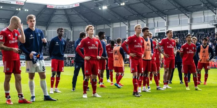 Die Spieler vom Hamburger SV stehen nach dem Spiel enttäuscht und geknickt auf dem Platz. Foto: Guido Kirchner