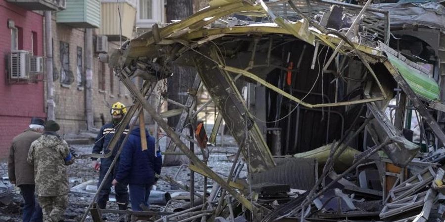 Soldaten stehen nach einem Bombenangriff auf einer Strasse in Kiew neben einer zerstörten Strassenbahn. Foto: Efrem Lukatsky/AP/dpa