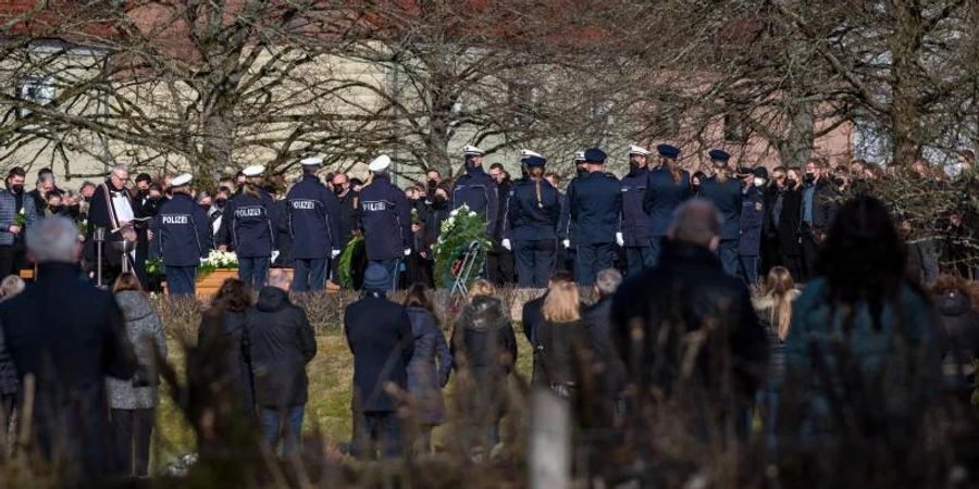Trauergäste, darunter viele Polizisten, stehen am Grab bei der Beisetzung des Polizisten in Freisen. Foto: Harald Tittel/dpa