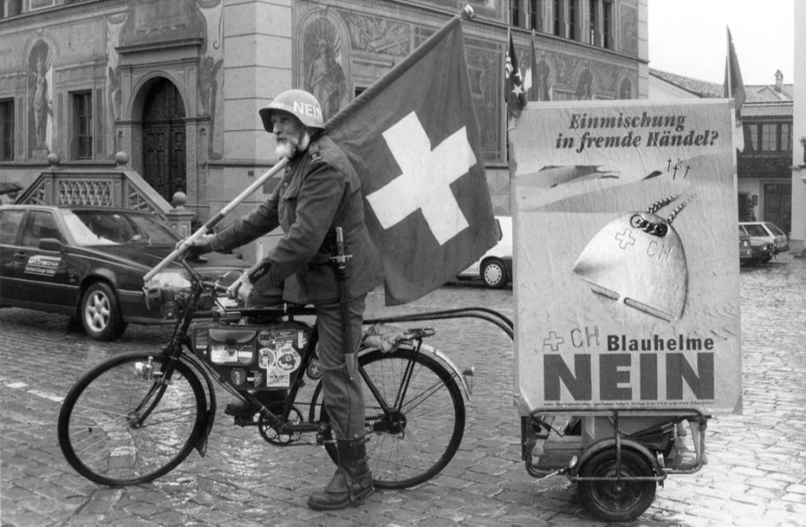 Der Abstimmungskampf über die sogenannte Blauhelm-Vorlage wurde seitens der Gegner teilweise mit unkonventionellen Methoden geführt. Hier ein als Soldat gekleideter Demonstrant, der mit Schweizerfahne, Helm und Messer gewappneten ein Plakat hinter sich herzieht.