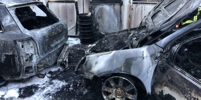 Drei Fahrzeuge in Flammen auf einem Parkplatz.