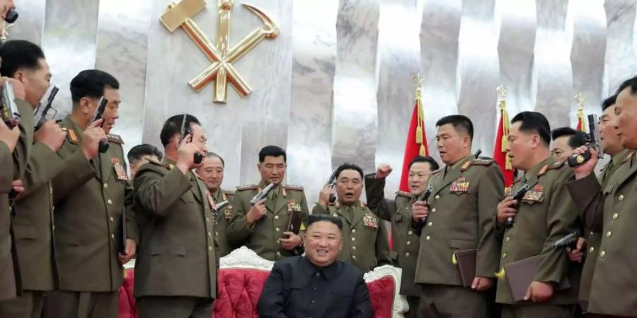 Nordkoreas Machthaber Kim Jong Un (M) sitzt während führende Kommandeure der Armee Waffen in der Hand halten. Foto: KCNA/dpa/Archiv