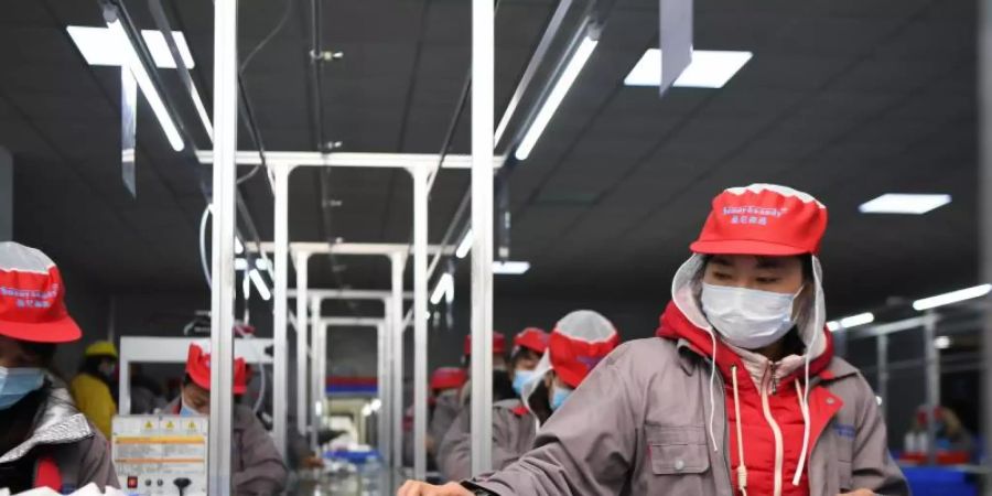 Menschen arbeiten in einer chinesischen Fabrik am Fliessband. Seit Jahren verhandeln die EU und China über einen faireren Wettbewerb. Foto: Xue Yuge/XinHua/dpa