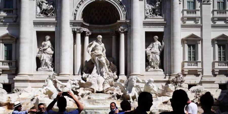 Touristen fotografieren den Trevi-Brunnen in Rom. Angesichts steigender Infektionszahlen wappnen sich manche Länder mit neuen Regeln. Foto: Evandro Inetti/ZUMA Wire/dpa