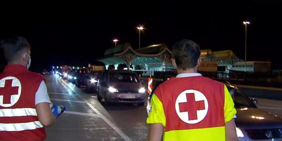 Mitarbeiter des Roten Kreuzes betreuen in der Nacht Autofahrer in einem kilometerlangen Stau bei der Einreise nach Österreich am Karawankentunnel. Foto: -/ORF KÄRNTEN/dpa