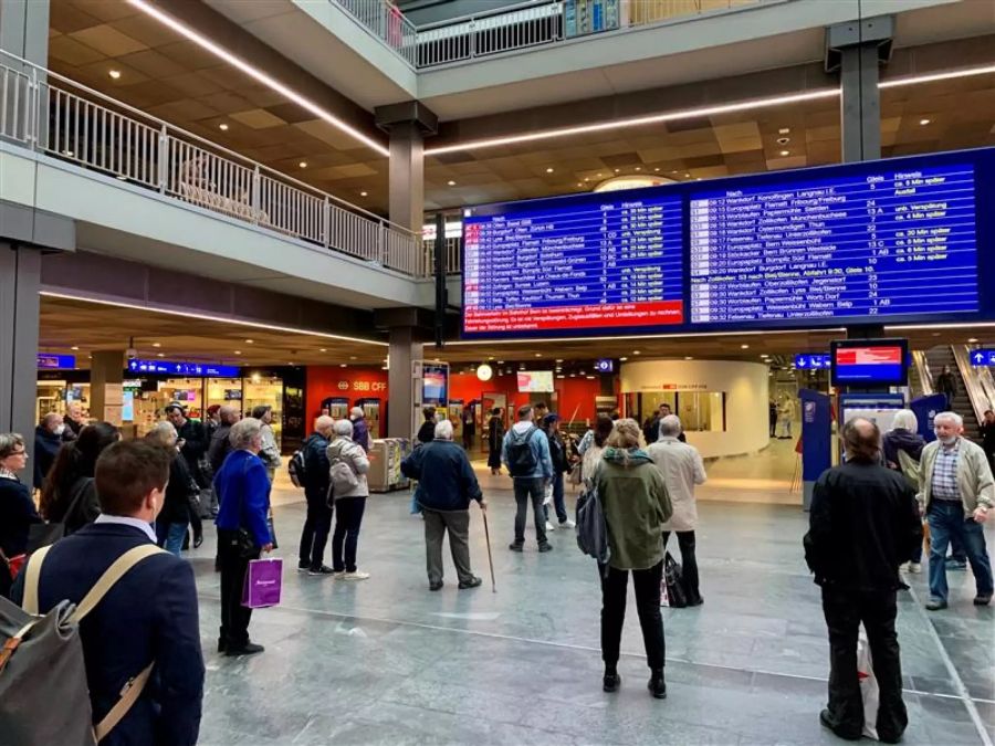 Pendler und Rentner schauen am Treffpunkt des Bahnhof Bern auf die Anzeigen mit den Zugverbindungen.