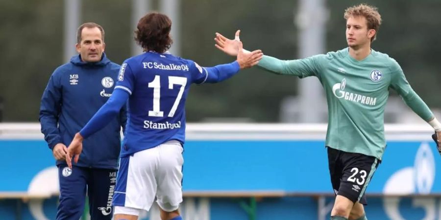 Manuel Baum (l) beordert bei seinem Heimdebüt Frederik Rönnow (r) ins Schalke-Tor. Foto: Guido Kirchner/dpa