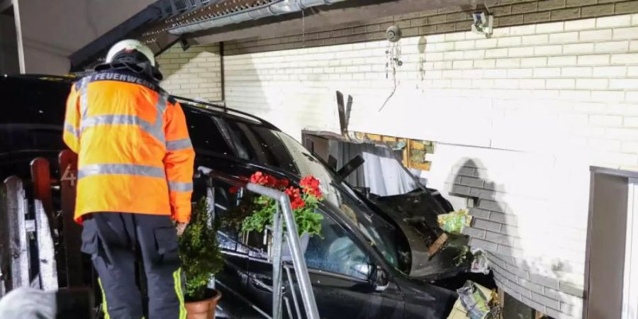 Rettungskräfte inspizieren das Auto, das in Wuppertal die Wand eines Wohnhauses durchbrochen hat. Foto: Tim Oelbermann/TV7News/dpa