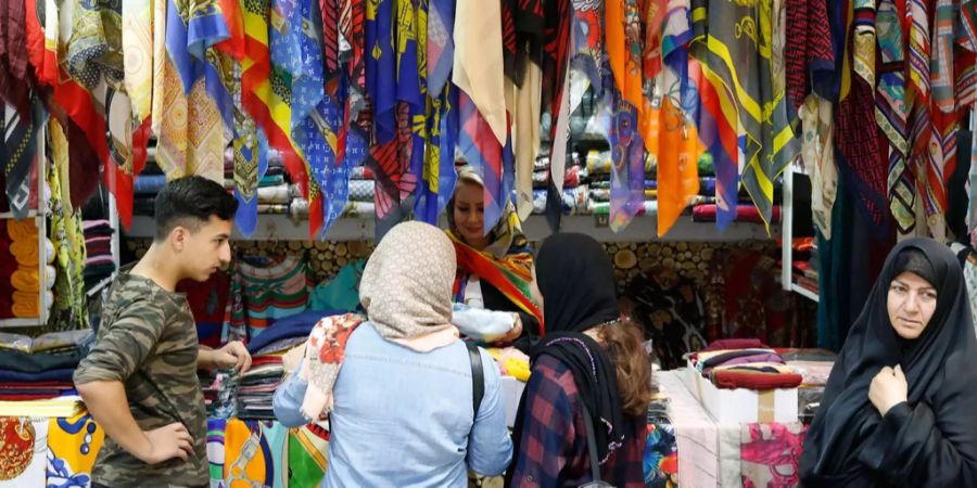 Iranerinnen nehmen an einem Bazar in Teheran Tücher in Augenschein.