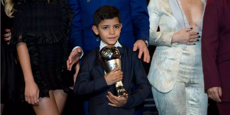 Cristiano Ronaldo junior (8) hält die Trophäe des Weltfussballers des Jahres seines Vaters.