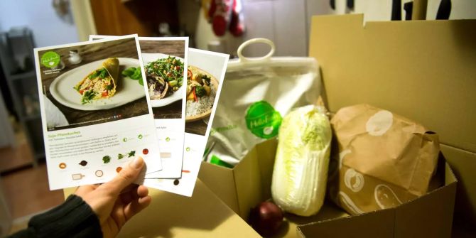 Ein Mann hält mitgelieferte Kochrezepte aus einer HelloFresh Kochbox in der Hand.