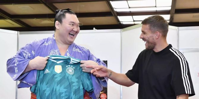 Lukas Podolski (r), Spieler des japanischen Fussballvereins Vissel Kobe, schenkt Sumo Grossmeister Hakuho (l) ein Trikot.