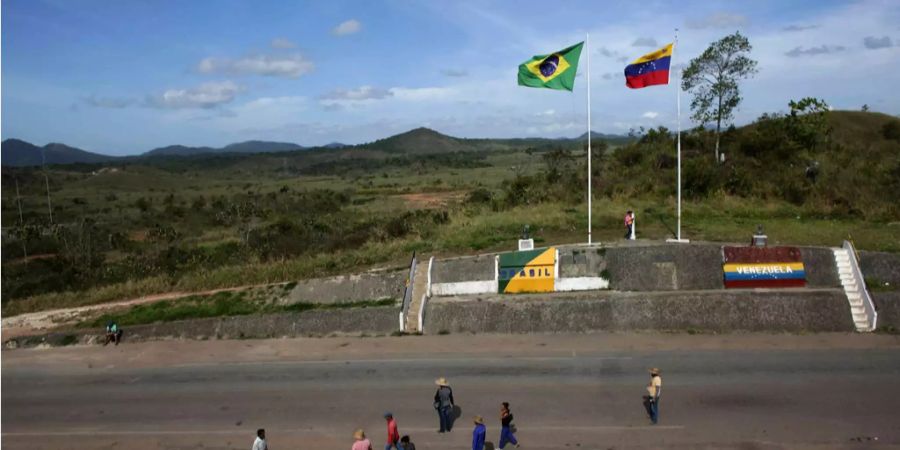 Menschen stehen an der Grenze zwischen Venezuela (rechts) und Brasilien (links).