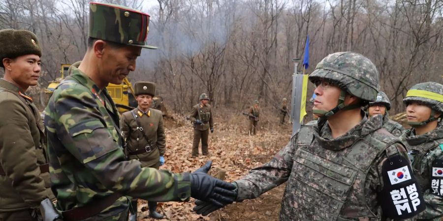 Ein südkoreanischer Soldat (r) und ein nordkoreanischer Soldat, geben sich die Hand.