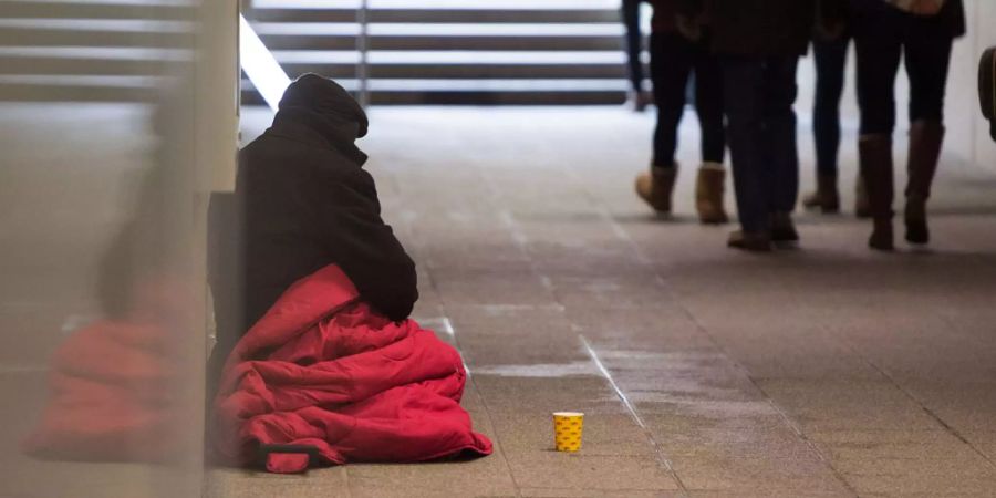 Ein Bettler sitzt in einer Unterführung