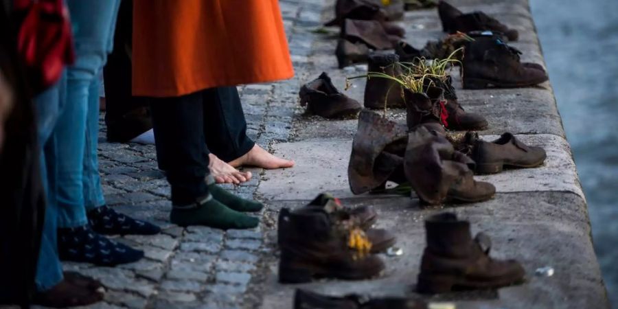 Trauernde legen ihre Schuhe zum Denkmal an der Donau.