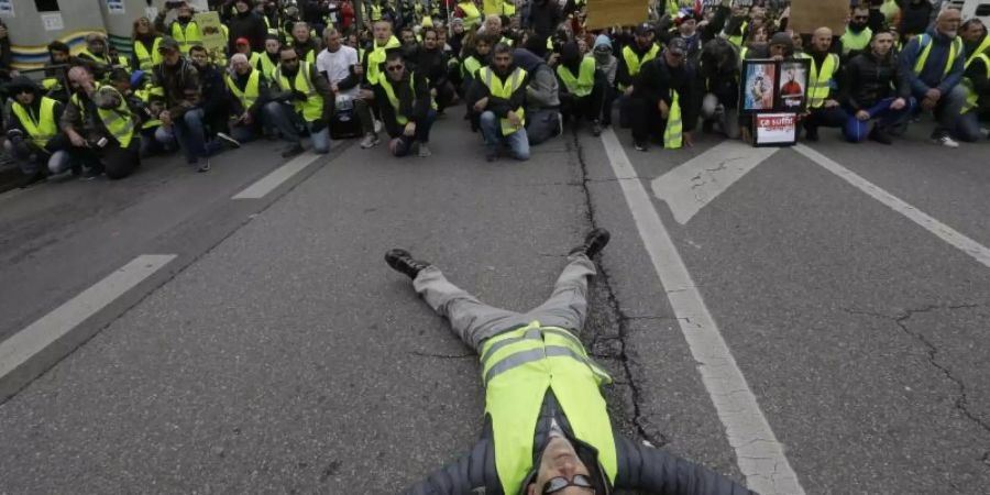 Ein Demonstrant liegt bei einem Protest der «Gelbwesten» in Marseille auf der Strasse. Foto: Claude Paris/AP