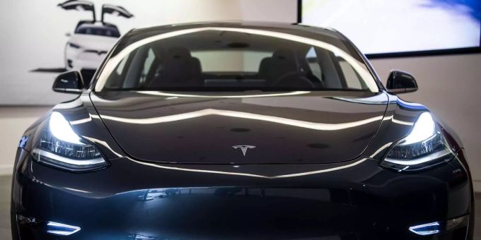 Auf der Motorhaube des Elektroautos Tesla Model 3in einem Ausstellungsraum ist das Logo zu sehen. tesla model 3