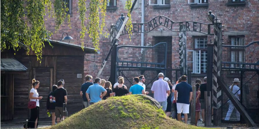 Besucher stehen vor dem Eingangstor zur KZ-Gedenkstätte Auschwitz (PL).